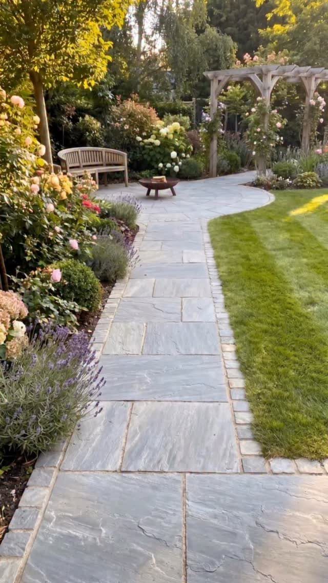 23 Backyard DIY Ideas for a Patio, Garden and Fire Pit 22 Stone walkway with decorative edging stones bordering a green lawn and flower beds.