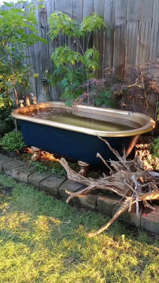 23 Backyard DIY Ideas for a Patio, Garden and Fire Pit 20 Dark blue clawfoot bathtub with gold rim placed in a lush outdoor garden setting.