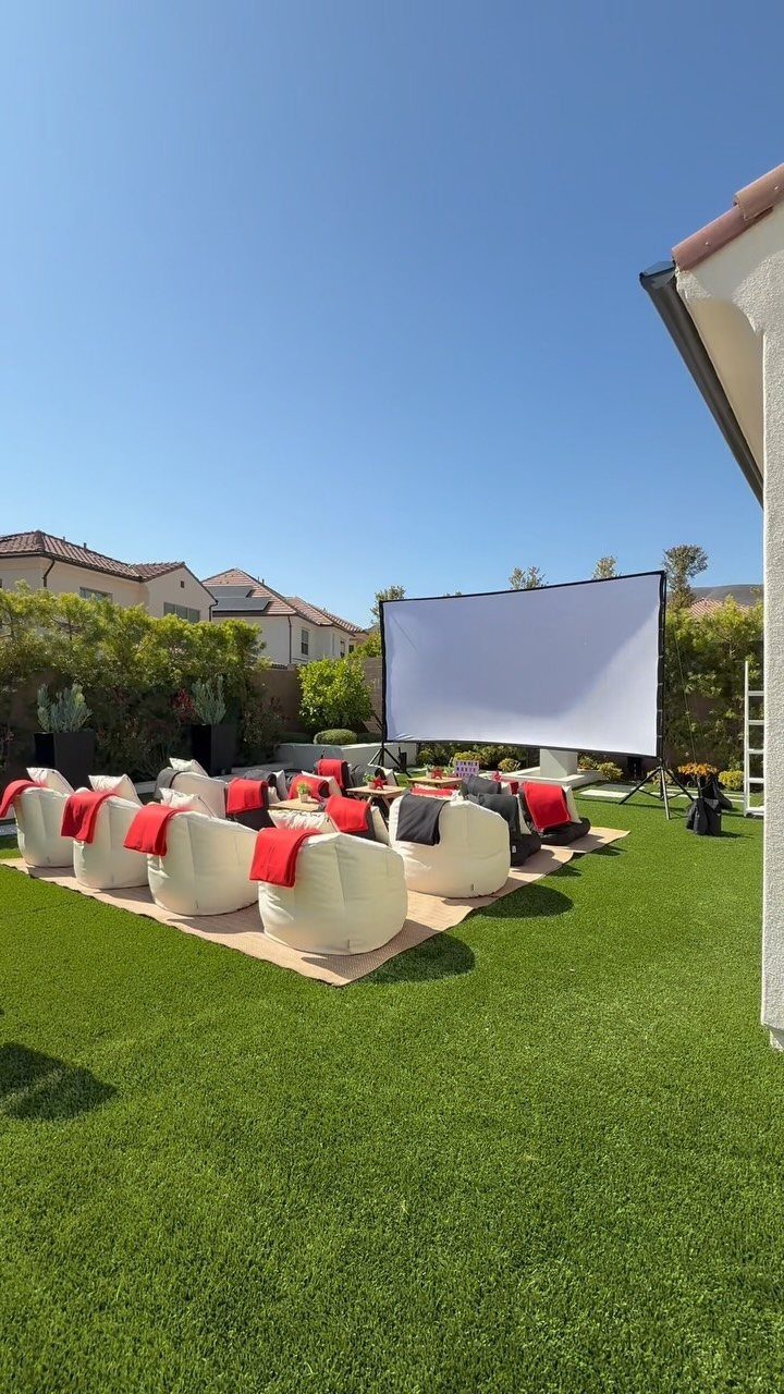 23 Backyard DIY Ideas for a Patio, Garden and Fire Pit 18 Large white projector screen and white bean bag chairs on a green backyard lawn.