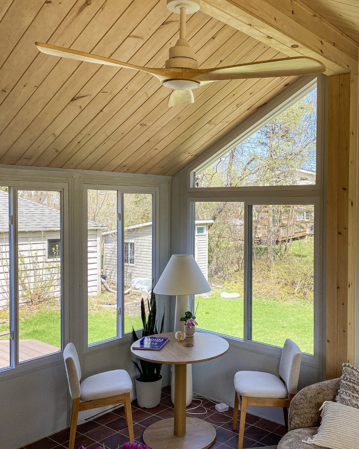 23 Backyard DIY Ideas for a Patio, Garden and Fire Pit 21 Sunroom with vaulted wood ceiling, large windows, and a small dining set.