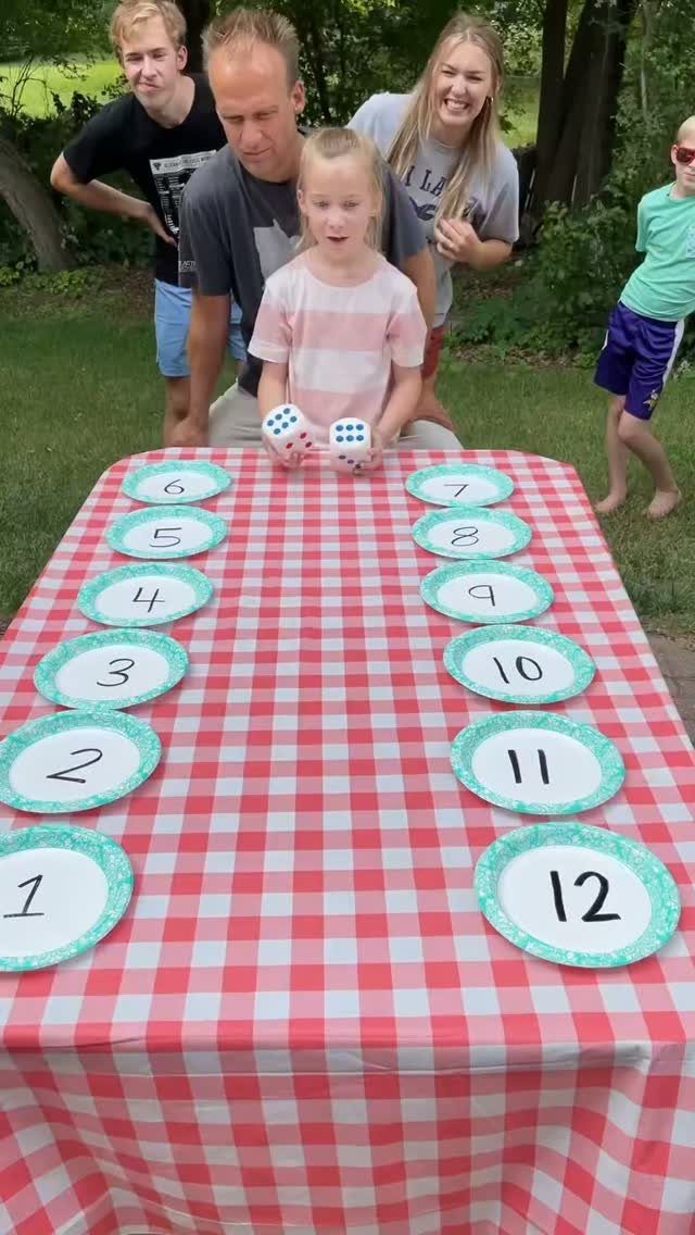 23 Backyard DIY Ideas for a Patio, Garden and Fire Pit 14 Family playing a game with oversized dice and numbered plates on a checkered table.