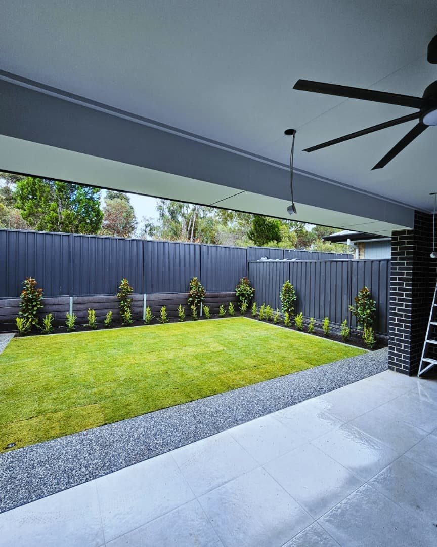 10 Backyard Fence Landscaping Ideas for Beautiful Borders 8 Modern backyard with grey metal fence and small shrubs in a narrow planting bed