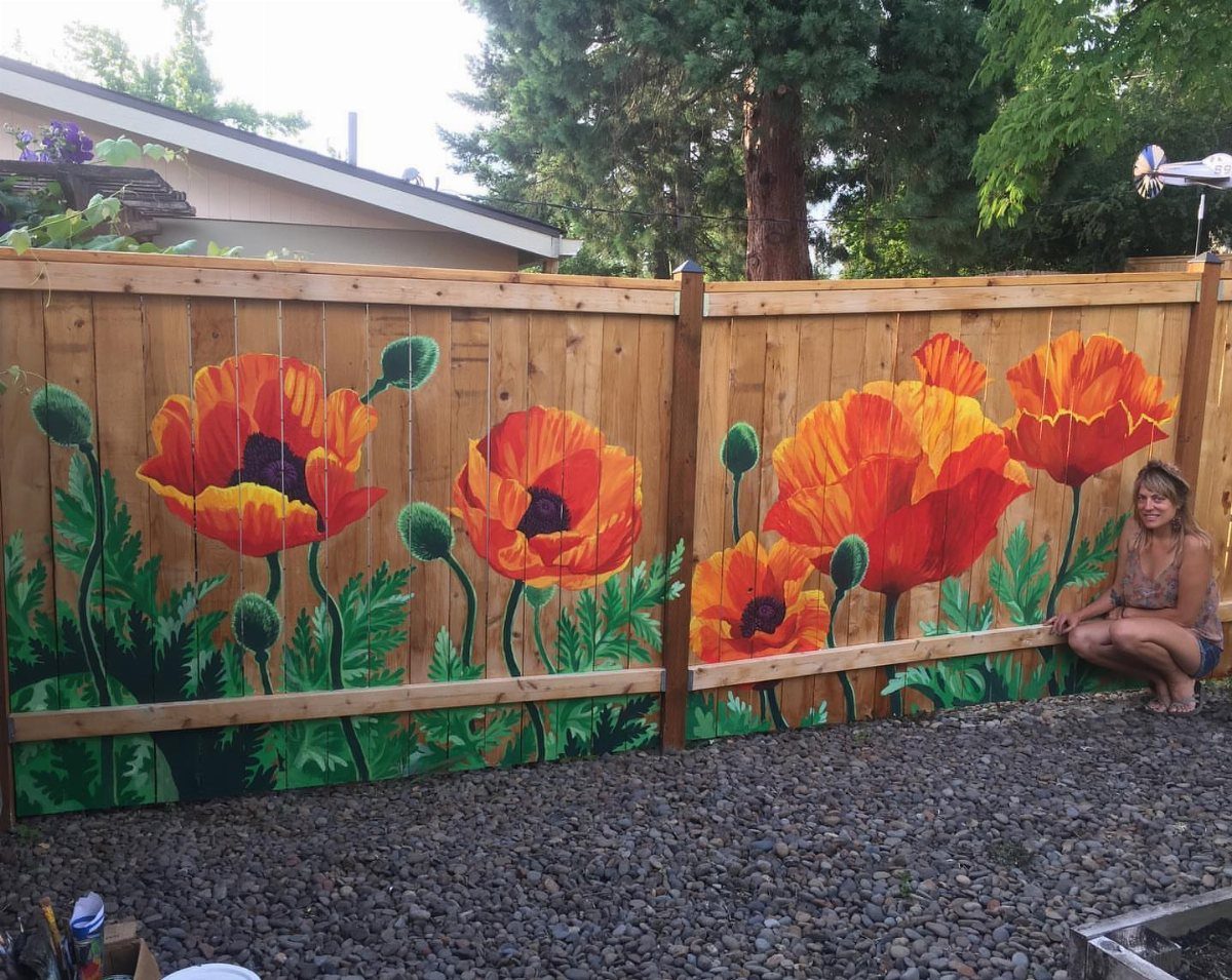 Wooden backyard fence with a colorful mural of large red and orange poppy flowers.