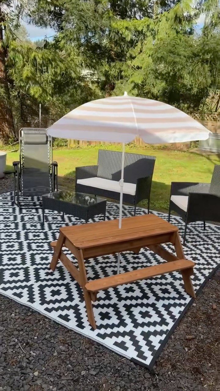 Black and white geometric outdoor rug with patio furniture and a striped umbrella.