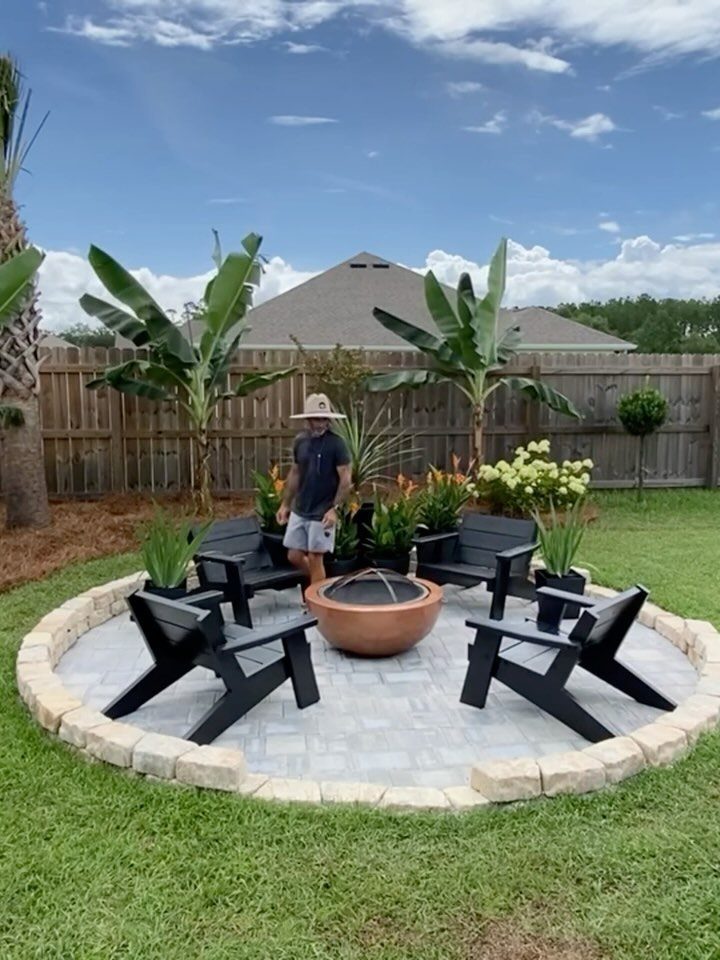 Copper bowl fire pit surrounded by black chairs on a circular stone patio.