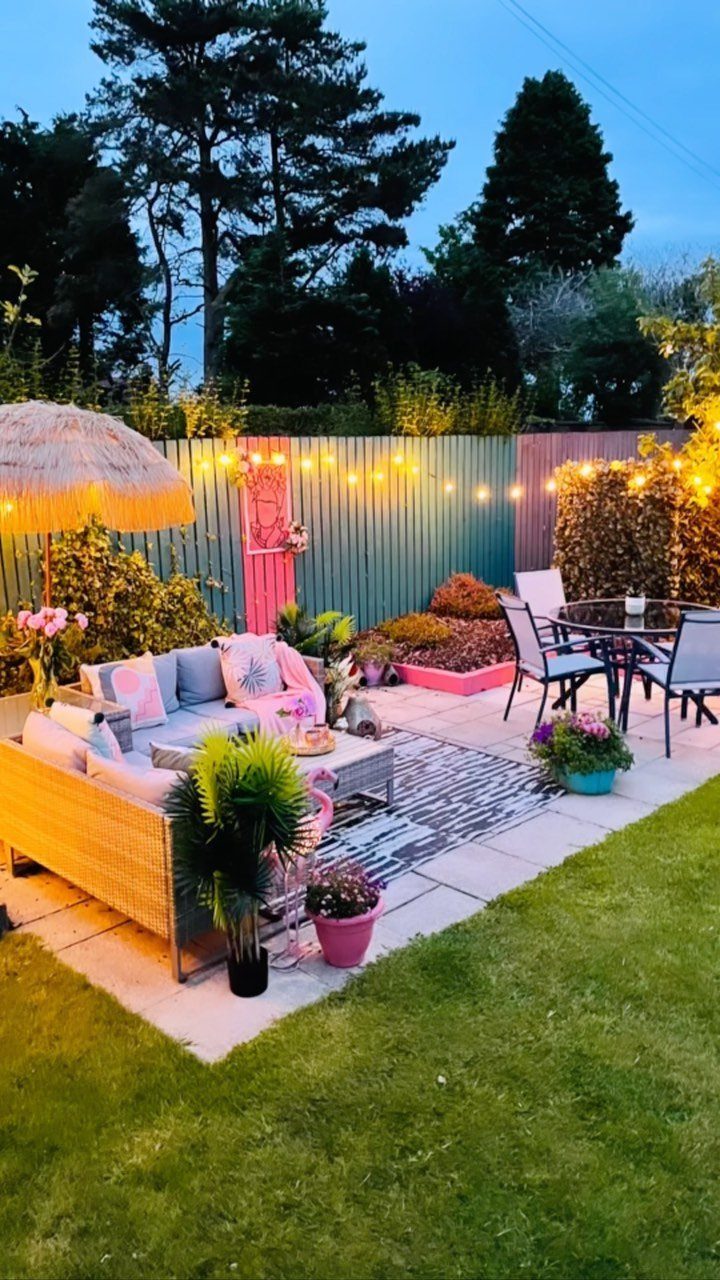 14 Cheap Garden Makeover Ideas to Refresh Your Yard 13 Wicker outdoor couch with grey cushions on a patio with string lights.