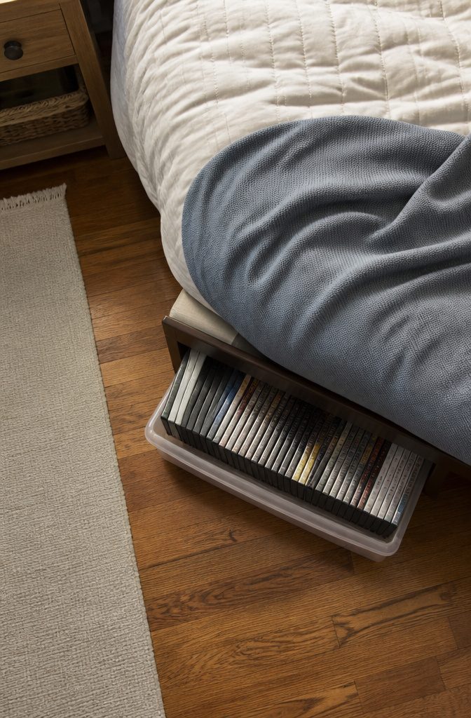 10 DVD Storage Ideas for Organizing Movies in 2026 5 Rubbermaid storage boxes for DVDs placed under a bed.
