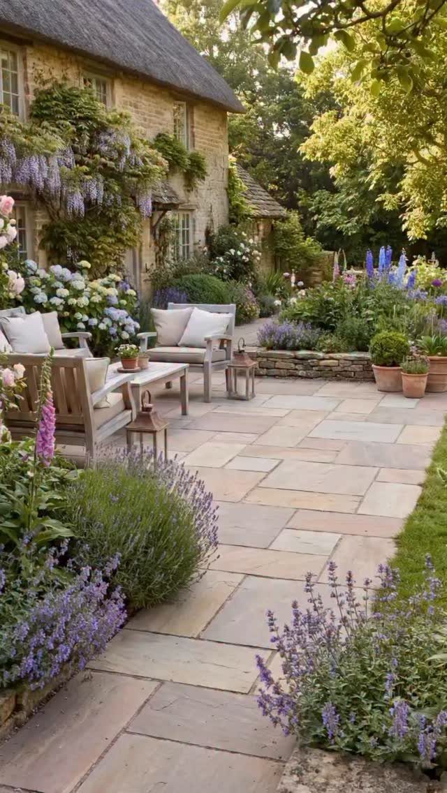 English Garden Design Ideas: 10 Classic Elements to Use 1 Stone patio with outdoor seating surrounded by abundant purple and blue cottage garden flowers.