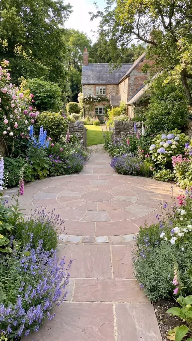 English Garden Design Ideas: 10 Classic Elements to Use 7 Stone garden path and circular patio surrounded by colorful blooming flowers and greenery.