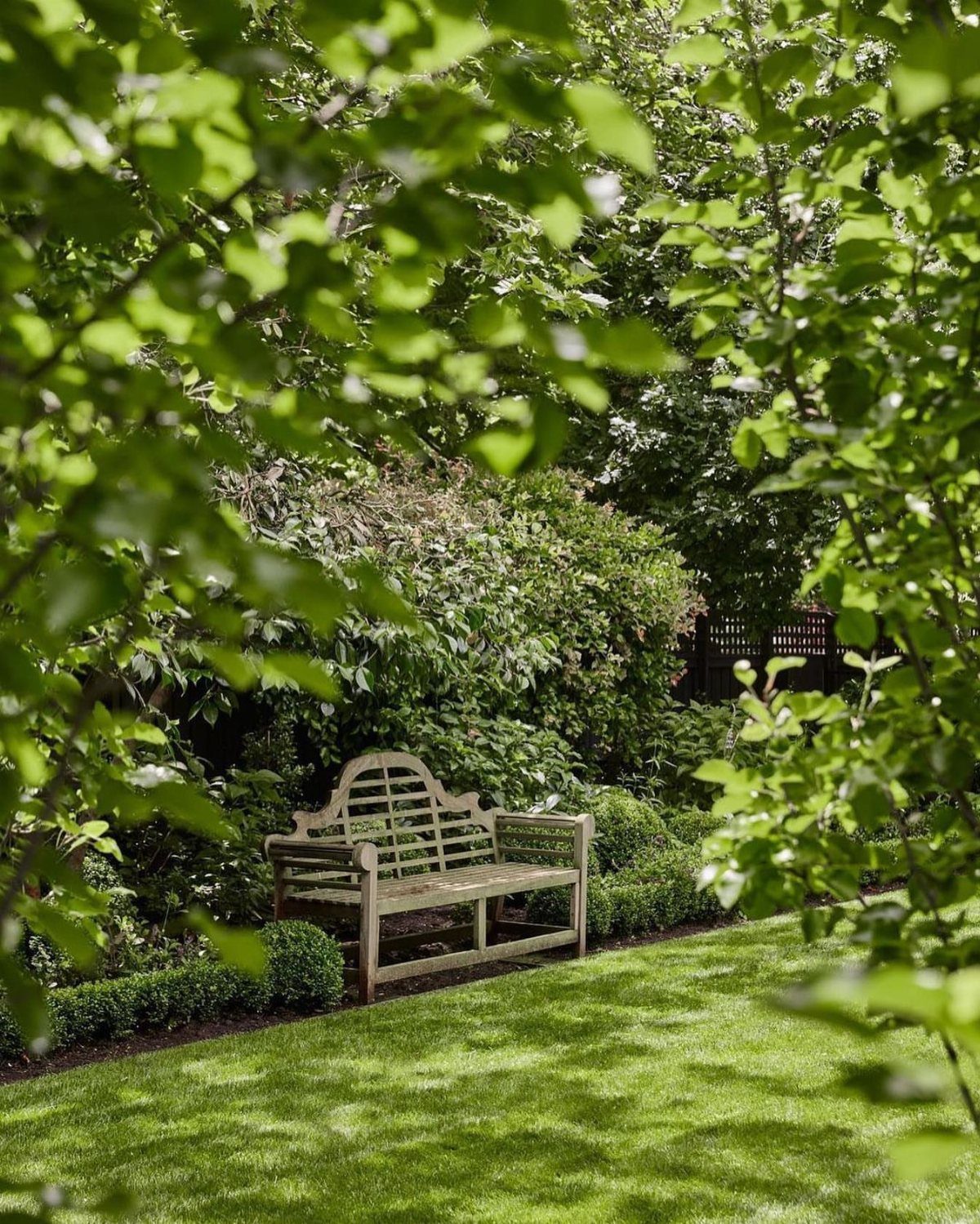 English Garden Design Ideas: 10 Classic Elements to Use 9 Wooden garden bench on a green lawn surrounded by lush green foliage and trees