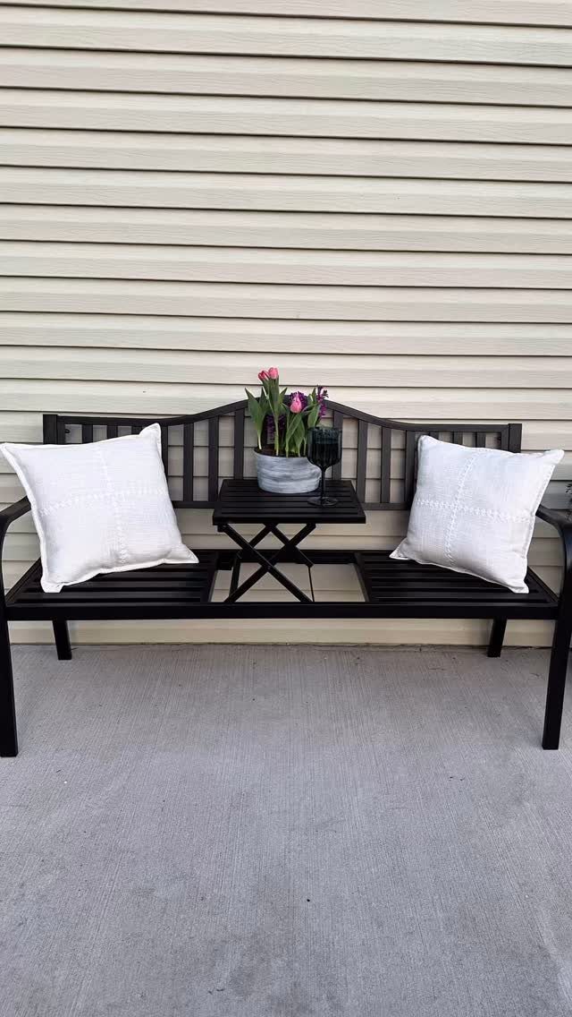 26 Front Garden Ideas for Curb Appeal and Small Yards 24 Black metal garden bench with white pillows and a small table of flowers.
