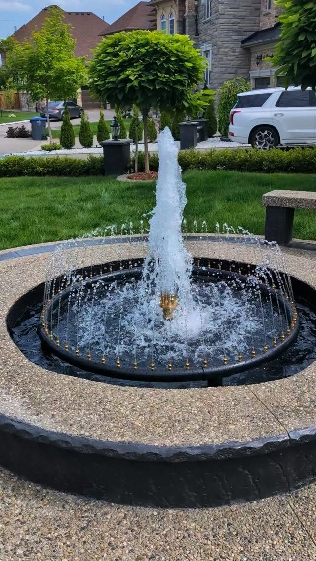 26 Front Garden Ideas for Curb Appeal and Small Yards 25 Circular black metal garden fountain spraying water in a manicured front yard.