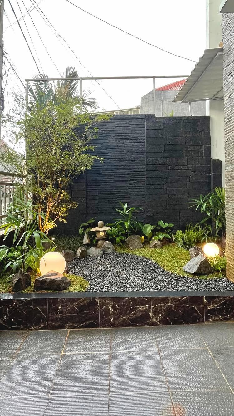 26 Front Garden Ideas for Curb Appeal and Small Yards 13 Zen garden with black textured wall, grey gravel, stone lantern, and glowing orb lights.