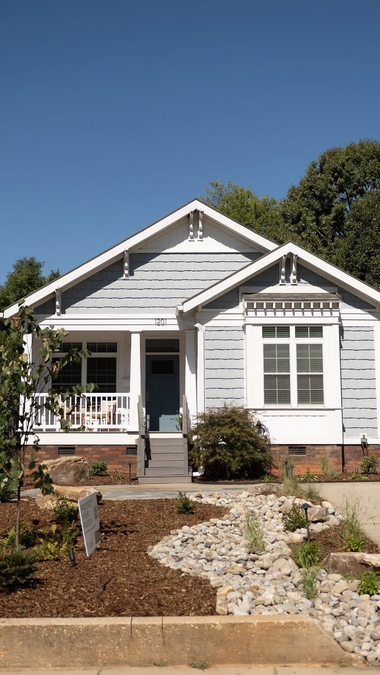 Grey house with a front yard featuring a stone dry creek bed and mulch.