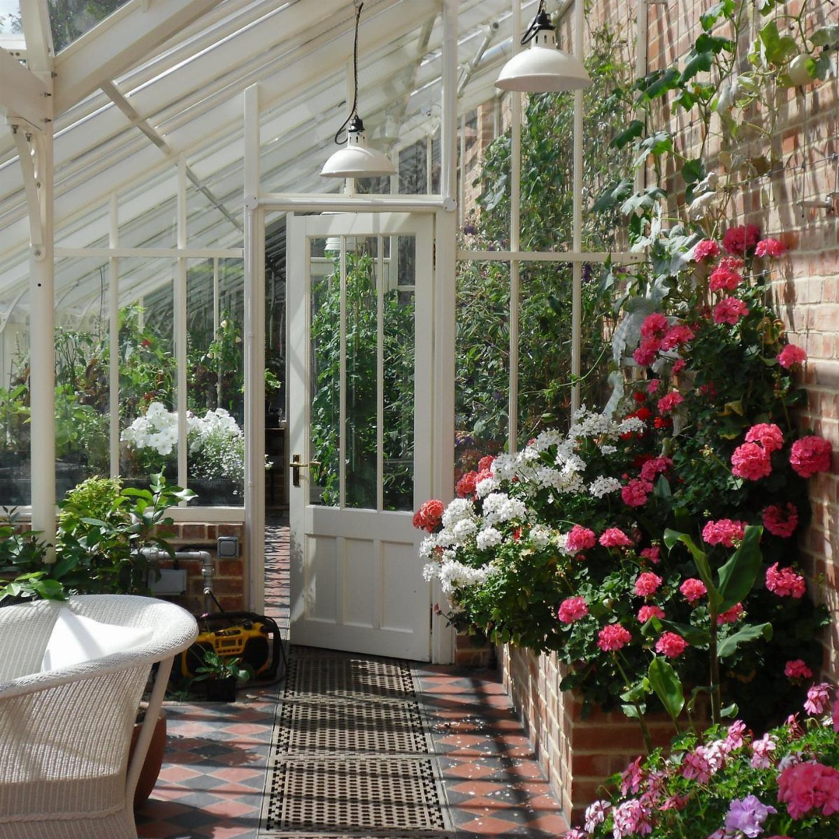 Green House Layout: 17 Ideas for Benches, Beds and Lighting 17 White glass greenhouse interior with brick walls, tiled floors, and vibrant pink flowers.