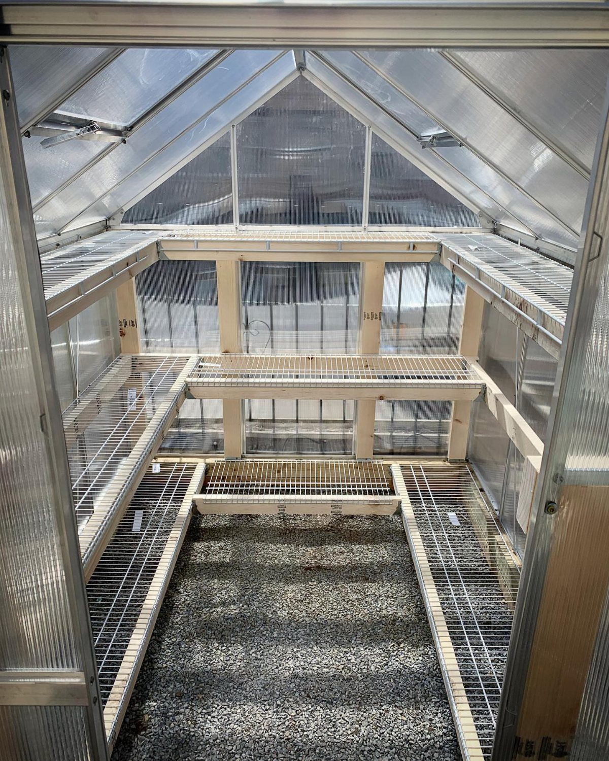 Interior of a steel potting shed with wire shelving and gravel floor.