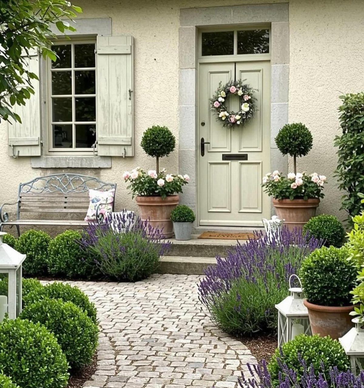 Cobblestone patterned pavers walkway lined with purple lavender and manicured green shrubs.