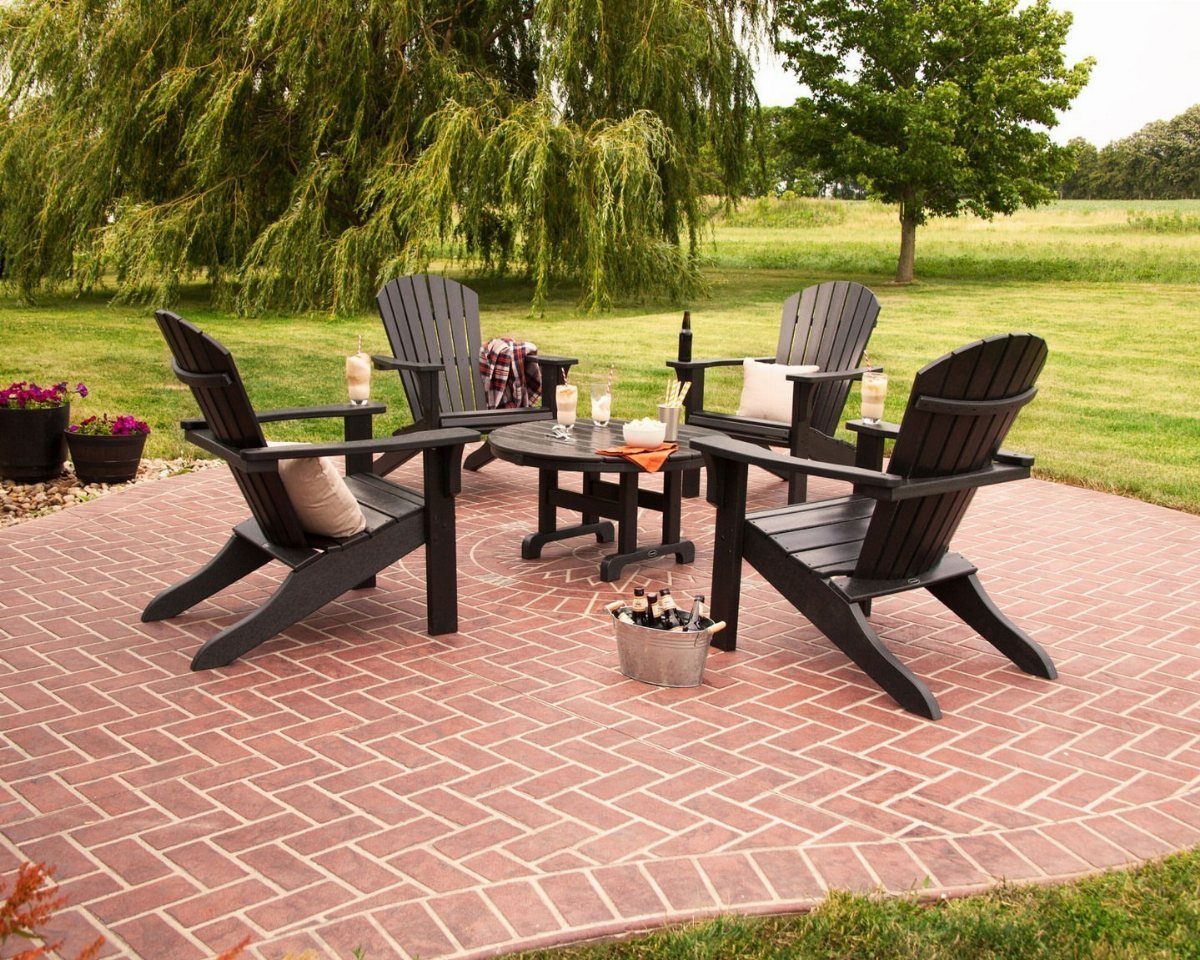 Black Adirondack chairs arranged in a circle around a small table on brick patio