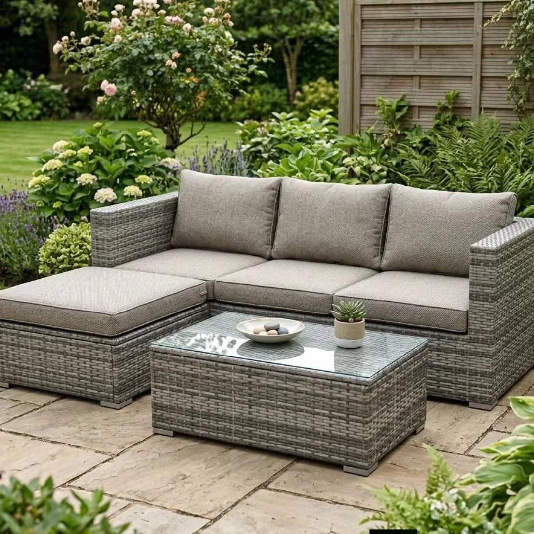 Grey wicker sectional sofa and coffee table on a stone garden patio.