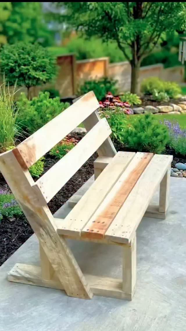 Wooden pallet bench on a concrete path in a green garden setting.