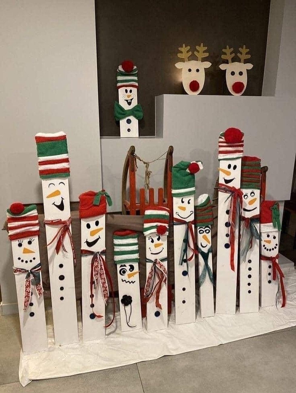 Wooden pallet snowmen with colorful hats and scarves standing in a festive row.