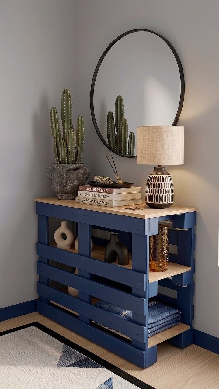 Blue pallet wood console table with a light wood top and decorative items.