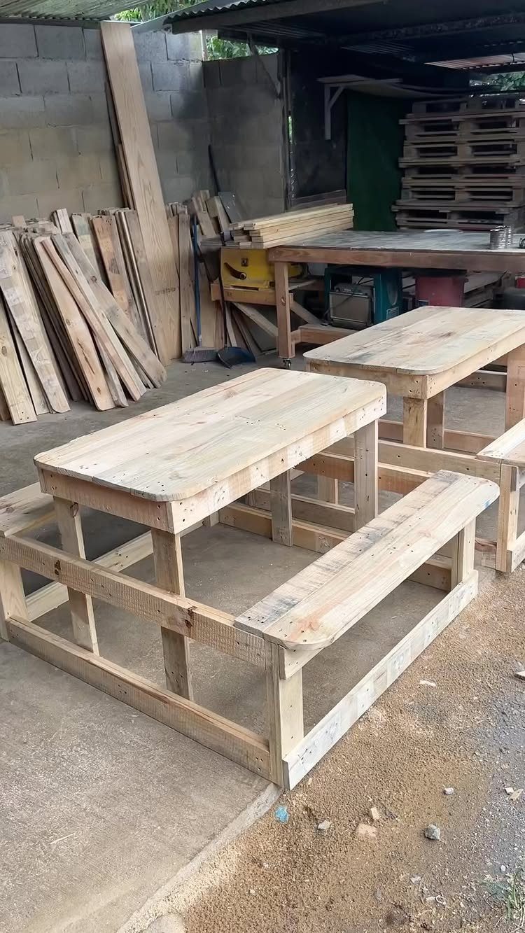 Wooden picnic table with benches made from light-colored pallet wood in a workshop.