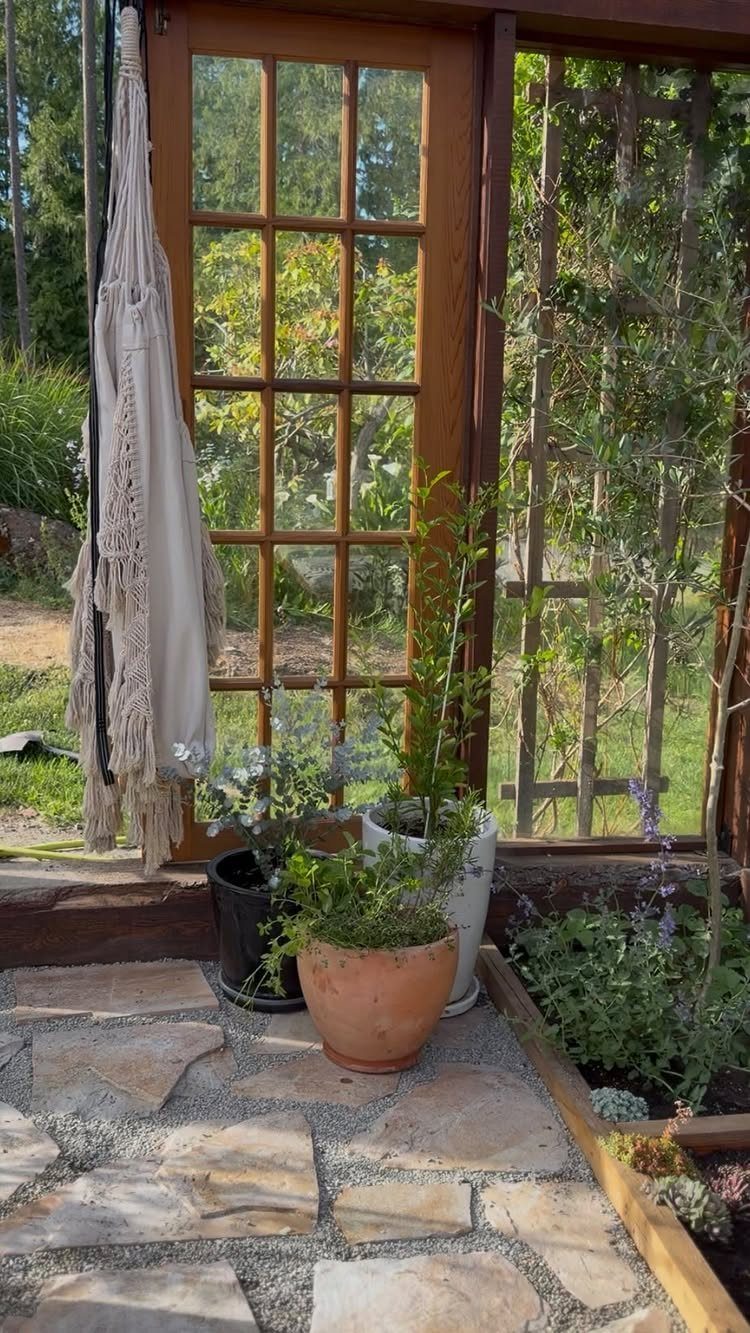 Flagstone floor with irregular light stones inside a wooden greenhouse with potted plants.