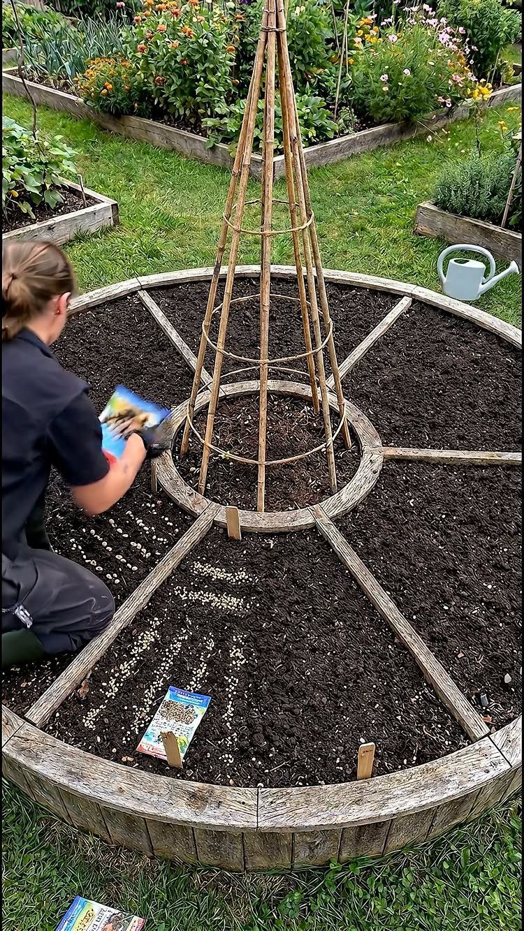 Raised Beds Garden: 25 Ideas from Wood, Metal, and Stone 22 Circular wooden raised garden bed with a central bamboo trellis and dark soil.