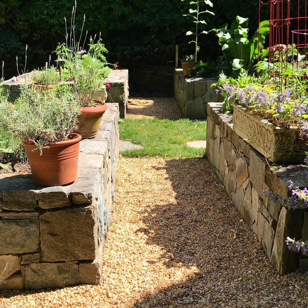 Raised Beds Garden: 25 Ideas from Wood, Metal, and Stone 14 Stone masonry raised garden beds with terracotta pots along a gravel path.
