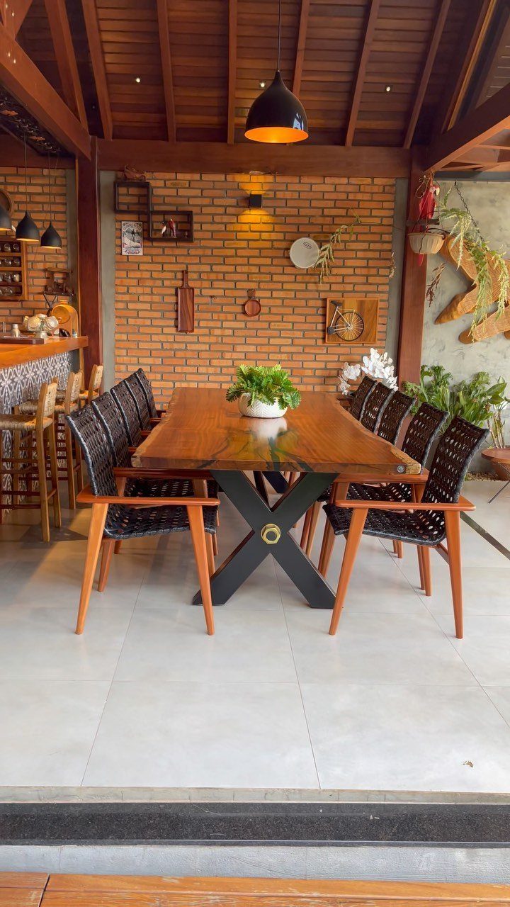 Polished wood dining table with black X-legs and woven chairs on a patio.