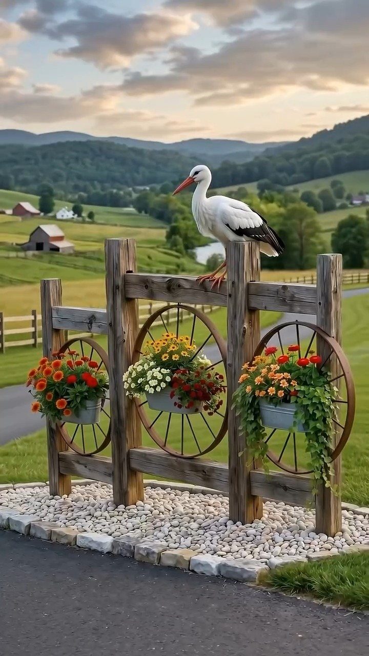Galvanized metal buckets with colorful flowers mounted on a rustic wooden fence with wagon wheels.