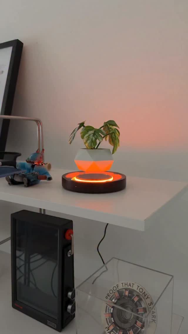 18 Unique Pots for Plants, From Resin Corgis to Copper Flowers 2 Levitating white plant pot floating above a glowing orange circular base on a shelf.