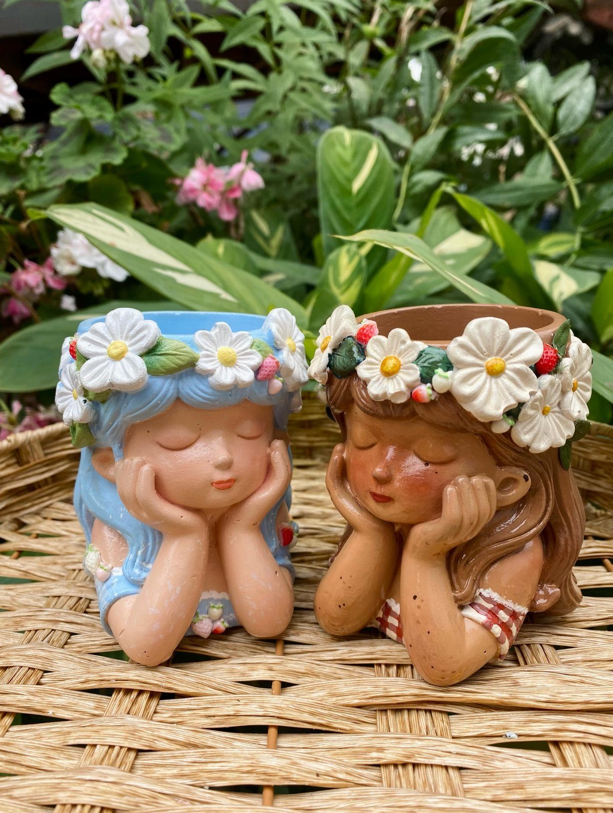 18 Unique Pots for Plants, From Resin Corgis to Copper Flowers 9 Two resin girl planters with flower crowns resting on a woven wicker surface.