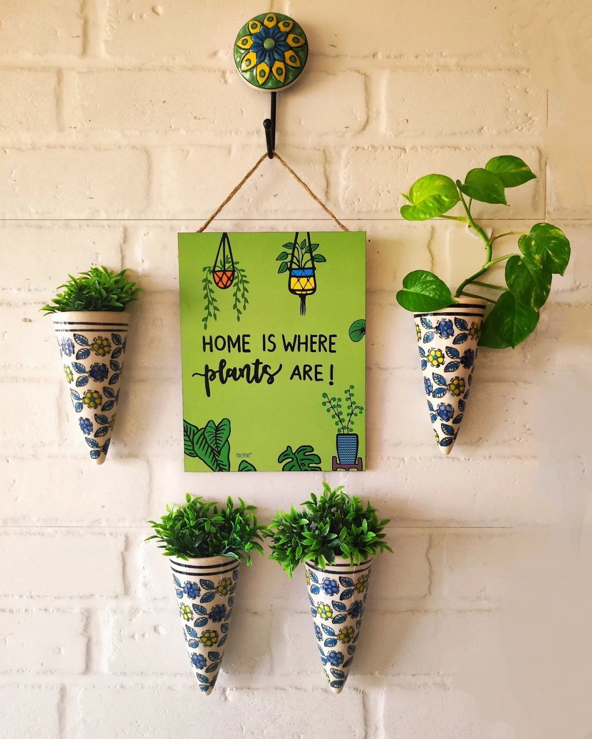 18 Unique Pots for Plants, From Resin Corgis to Copper Flowers 16 Cone-shaped ceramic planters with blue floral patterns mounted on a white brick wall.